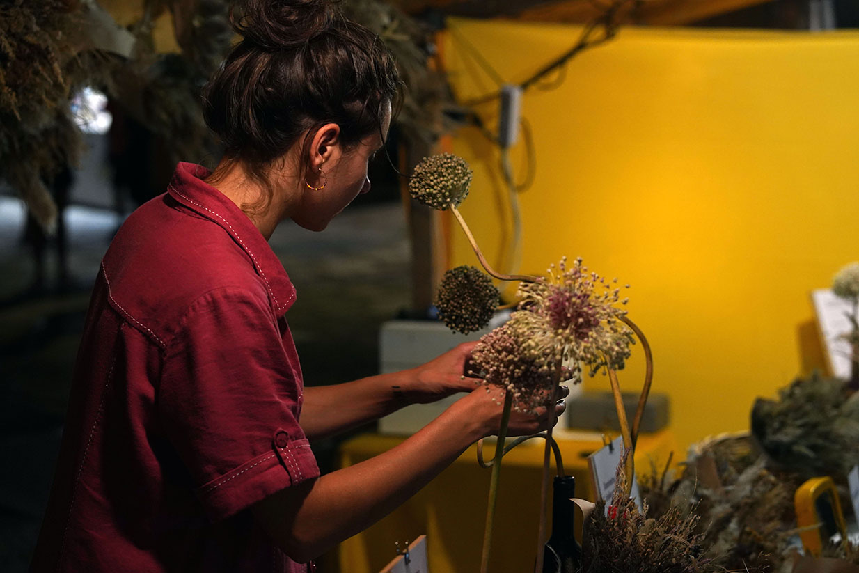 Stand de marché artisanal avec artisan réalisant des compositions florales au sein de son atelier boutique ambulant