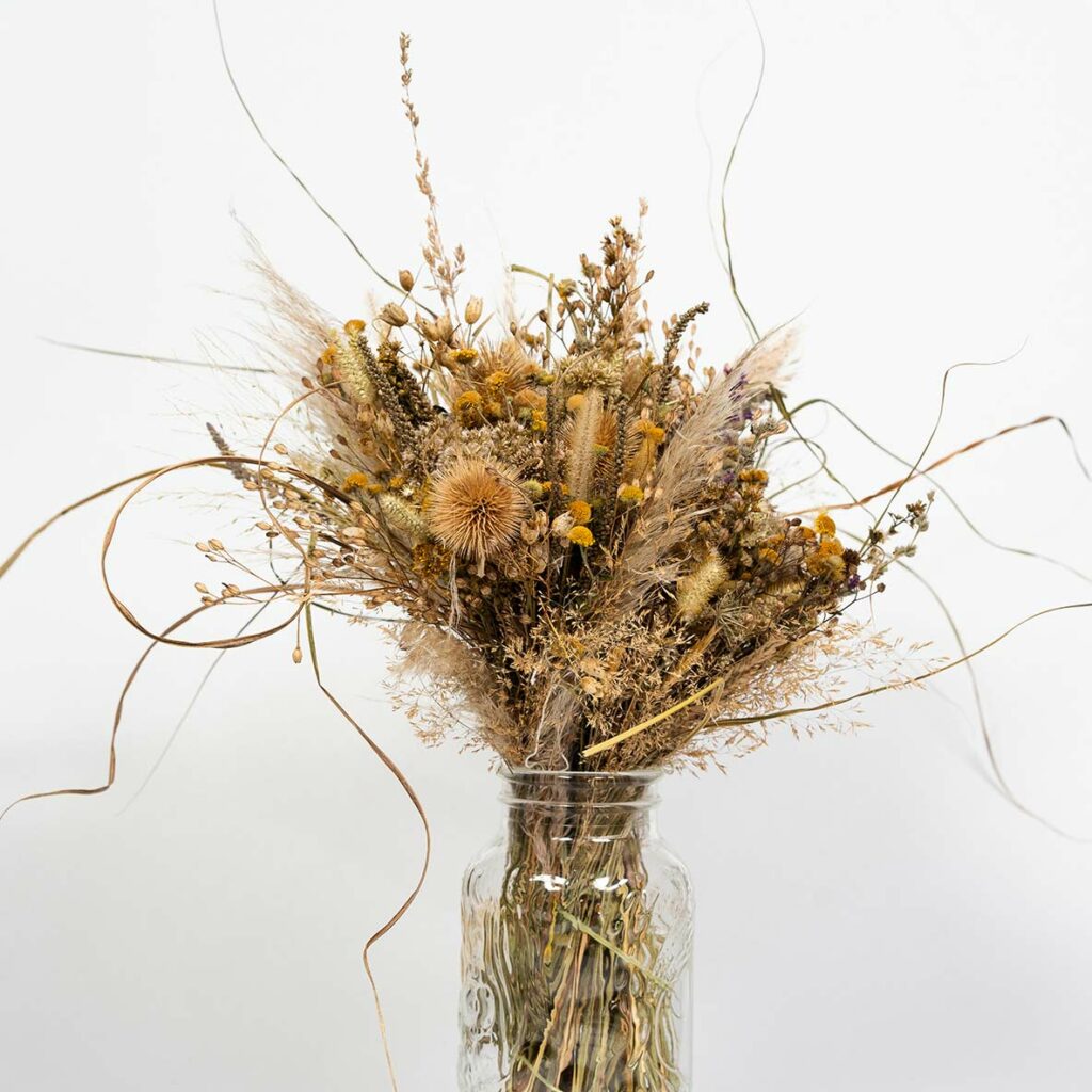 Grand bouquet de fleurs séchées avec chardons et pampas dans un vase en verre transparent reélisé à l'occasion d'un atelier créatif et artisanal