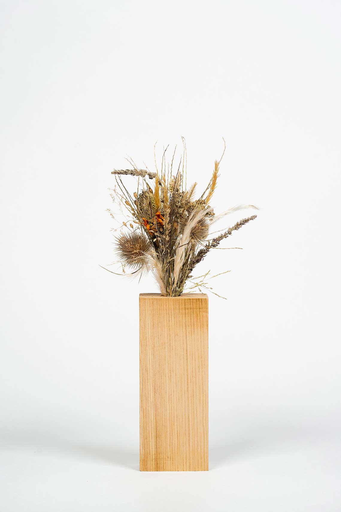 Moyen socle en bois fait main avec un bouquet de fleurs séchées