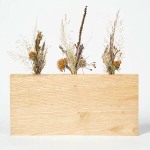 Grand socle artisanal en bois clair contenant trois mini bouquets de fleurs séchées