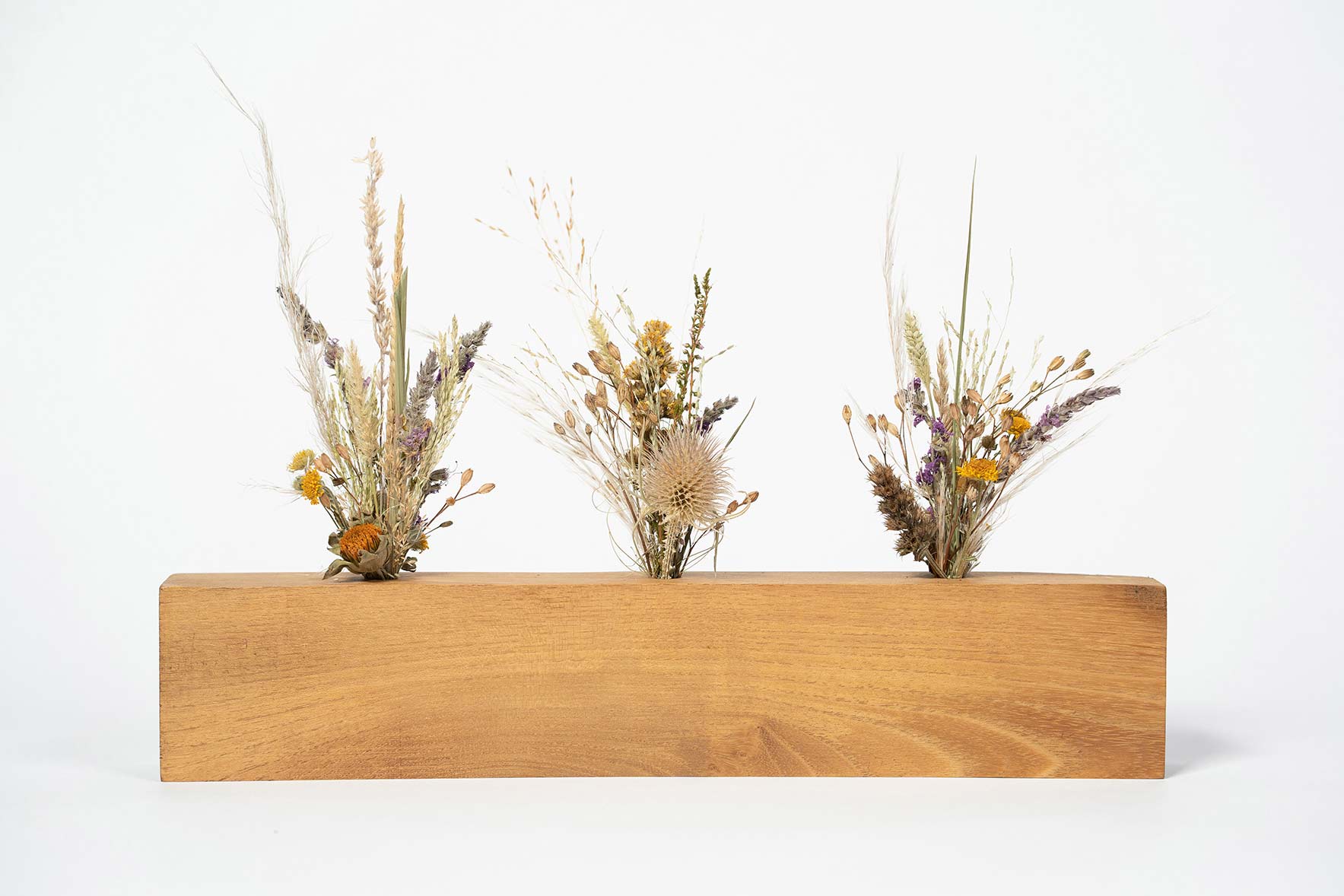 Socle artisanal en bois contenant trois mini bouquets de fleurs séchées