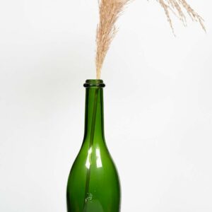 Vase en verre type gross bouteille verte contenant des fleurs séchées type pampas