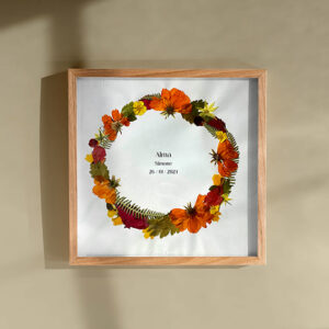 Couronne de fleurs préssées pour un cadeau de naissance . Fleurs oranges, vertes, jaunes dans un cadre